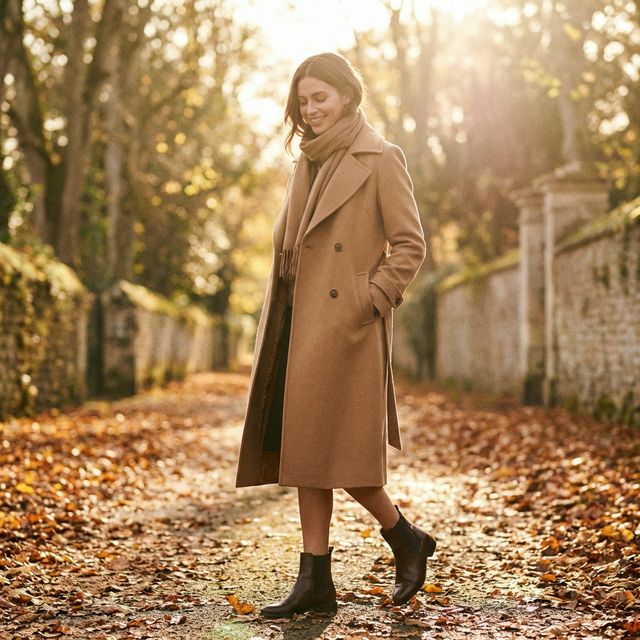 Moda otoñal: modelo con abrigo camel entre hojas doradas