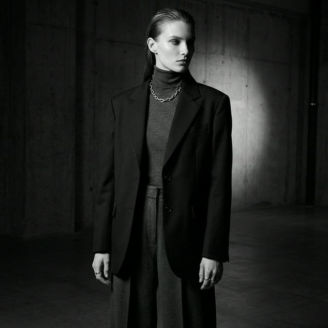 Modelo con look oscuro elegante: blazer oversize y collar de cadena